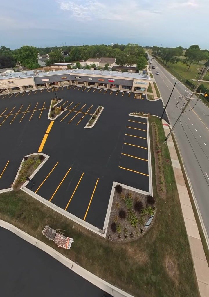 Aerial view of a shopping center's freshly sealed and striped parking lot